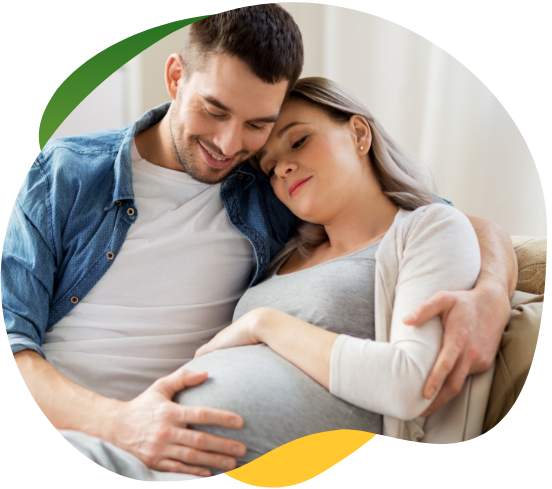 Tehotná žena, ktorá trpí nadúvaním, sedí so zatvorenými očami na pohovke. Jej partner ju drží v náručí a utešuje ju