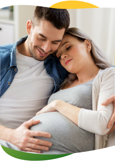 Tehotná žena, ktorá trpí nadúvaním, sedí  so zatvorenými očami na pohovke. Jej partner ju utešuje a drží ju v náručí.