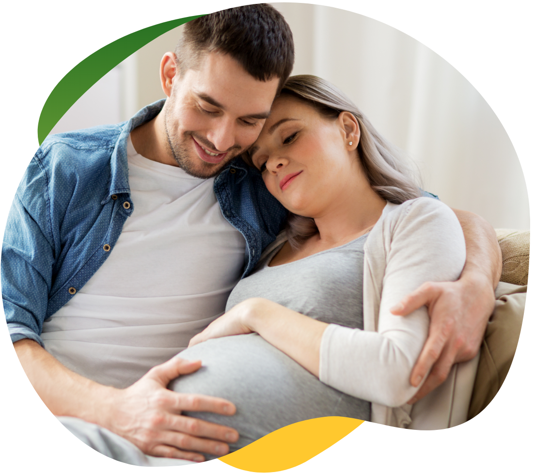 Tehotná žena, ktorá trpí nadúvaním, sedí so zatvorenými očami na pohovke. Jej partner ju drží v náručí a utešuje ju.