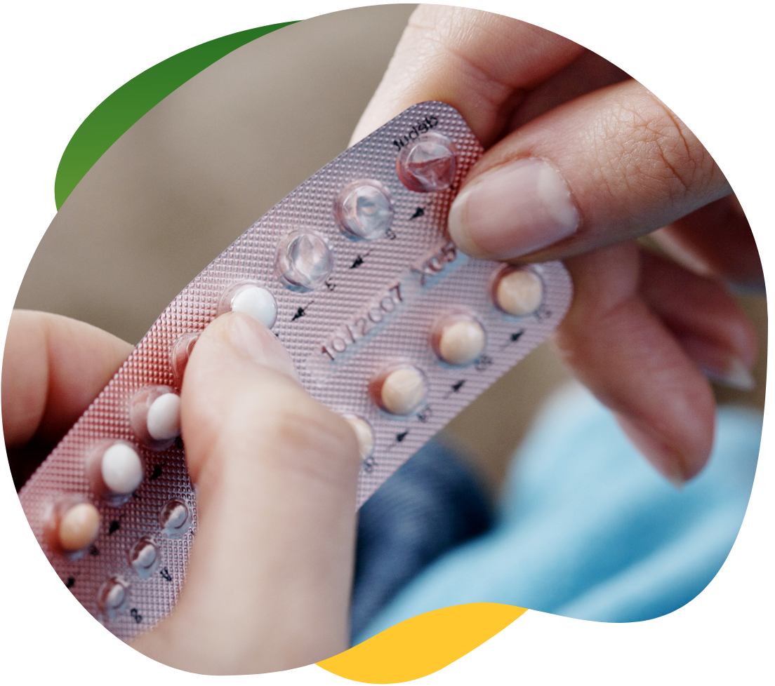 Ženské ruky vytláčajú antikoncepčnú tabletku z obalu