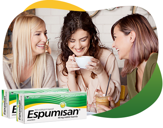 Tri priateľky pijú kávu a dobre sa zabávajú, vymieňajú si informácie o nadúvaní a Espumisane. V popredí je zobrazené balenie kapsúl Espusiman 40 mg.