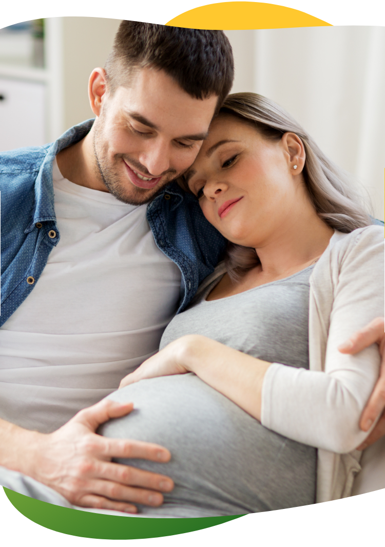Tehotná žena, ktorá trpí nadúvaním, sedí so zatvorenými očami na pohovke. Jej partner ju drží v náručí a utešuje ju